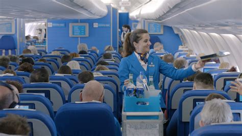 Een KLM cabin attendant die passagiers verwelkomt.