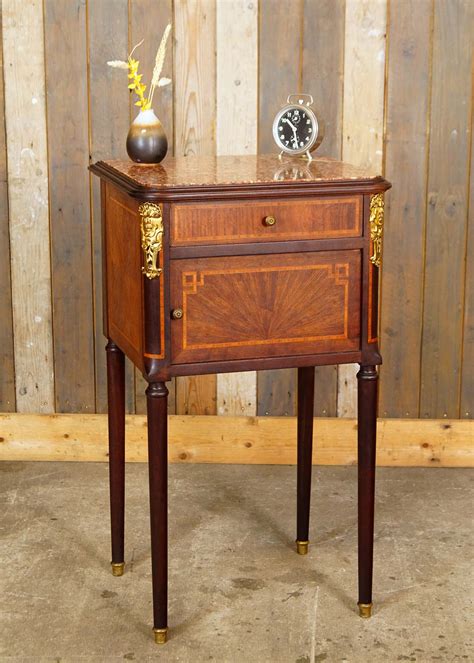 Een stijlvol marmeren nachtkastje met een messing tafellamp en een vaas met bloemen, als voorbeeld van luxe details in een slaapkamer.