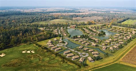 Luchtfoto van het toekomstige Roompot vakantiepark Someren, met de kenmerkende rieten kappen en de natuurlijke omgeving.