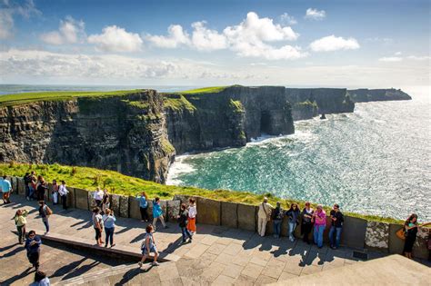Foto van de indrukwekkende Cliffs of Moher met toeristen die langs de rand lopen.
