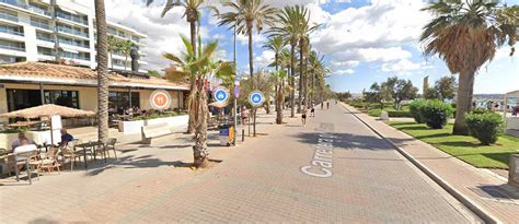 Levendige boulevard van Playa de Palma met parasols op het strand en gezellige terrasjes.