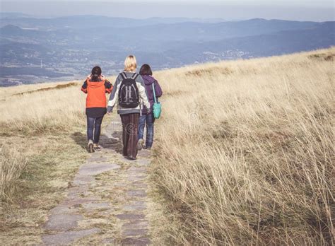 Groep wandelaars op een bergpad met uitzicht op een vallei