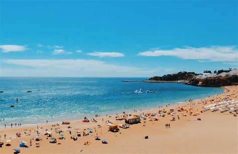 Breed zandstrand van Albufeira met ligbedden, parasols en de kenmerkende rotsformaties