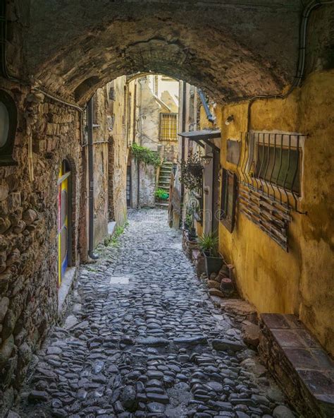 Een sfeervolle, smalle straat in Bussana Vecchia met kleurrijke kunstwerken aan de muren.