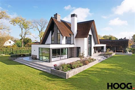 Een ruime, moderne villa met meerdere terrassen, omringd door een groen gazon, op een zonnige dag.