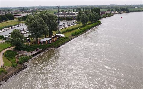 een boot die vaart op de Oude Maas met op de achtergrond een recreatiepark
