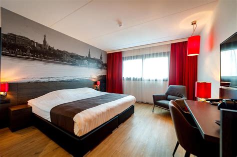 Moderne hotelkamer in Bastion Hotel Nijmegen met comfortabele bedden en een bureau.