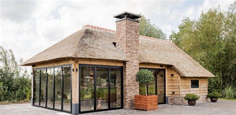 Vakantiewoning met rieten dak, omringd door groen