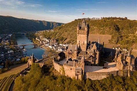 de Reichsburg Cochem op een heuvel met de Moezel op de voorgrond