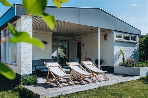 Huisje in de duinen met een hond die vrolijk rondrent.