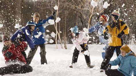 een kind dat lachend in een sneeuwballengevecht is met familieleden voor een appartement