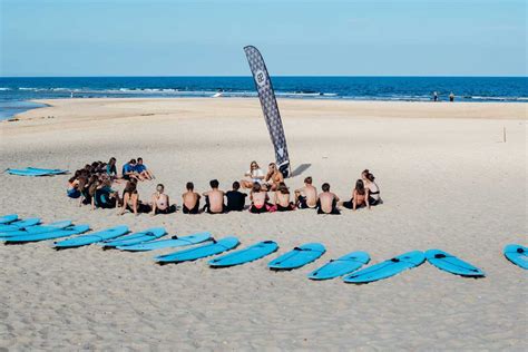 Zomerse taferelen op een Nederlands surfstrand met mensen die leren surfen.
