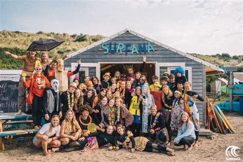 Groep jongeren lacht en geniet tijdens een surfkamp aan de Nederlandse kust.