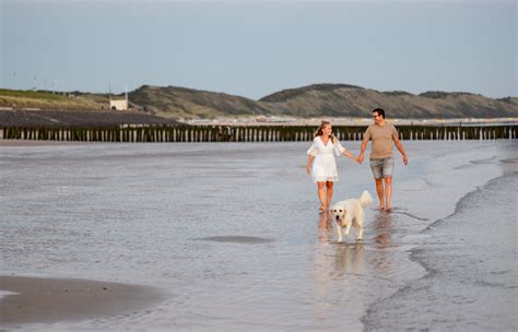 Familie geniet van een strandwandeling met hond in Zeeland