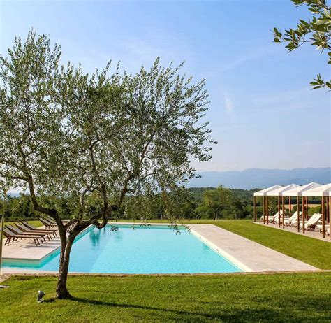 Een foto van een charmante agriturismo omgeven door olijfbomen, met een zwembad en uitzicht op de glooiende heuvels.