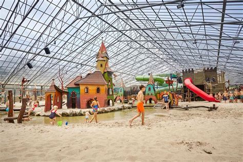 Kinderen spelen vrolijk in een kleurrijke indoorspeeltuin op een vakantiepark.