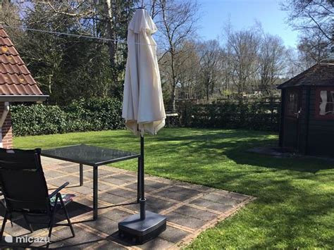 Een foto van de ruime, groene tuin van Vakantiehuis De Buizerd met tuinmeubelen en een barbecue.
