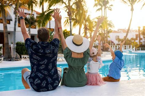 Een gezin genietend van het zwembad bij hun vakantiehuis, de kinderen spetteren terwijl de ouders ontspannen op ligstoelen.