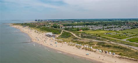Luchtfoto van vakantiepark EuroParcs Schoneveld met het strand en de zee op de achtergrond