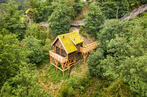 Diverse hutten van Les Cabanes de Rensiwez, genesteld in de natuurlijke omgeving van de Ardennen, met opties aan het water en tussen de bomen.