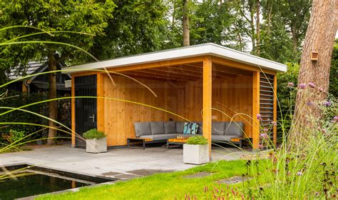 Een sfeervolle houten gîte met een buitenjacuzzi en uitzicht op een weelderige tuin.
