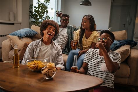 Een groep vrienden die samen lacht en geniet in een gezellige woonkamer van een vakantiehuis.