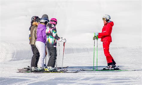 Een skileraar geeft les aan een groep beginners op een zonnige skipiste