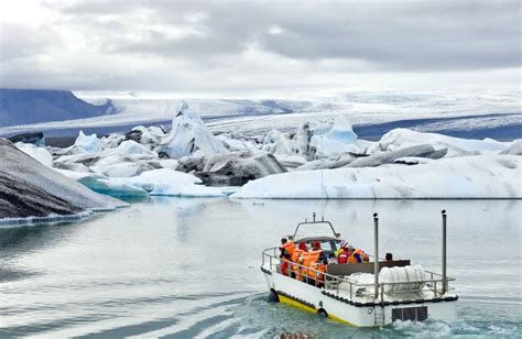 Een zodiac boot vaart tussen grote ijsbergen op de Fjallsárlón gletsjerlagune.