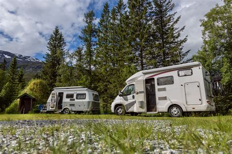 Een groep kampeerders met hun campers op een camping in IJsland met een bergachtig landschap op de achtergrond.