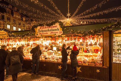 Een sfeervolle foto van een Duitse kerstmarkt met versierde kraampjes en verlichte bomen.