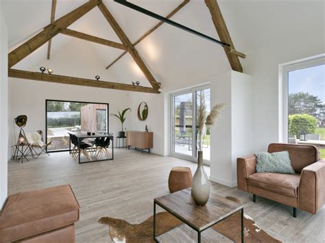 Interieur van een grote woonkamer met houten balken en een open wenteltrap