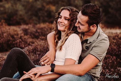 Foto van een koppel dat geniet van een jacuzzi in de sneeuw, met een huis met een verlichte open haard op de achtergrond