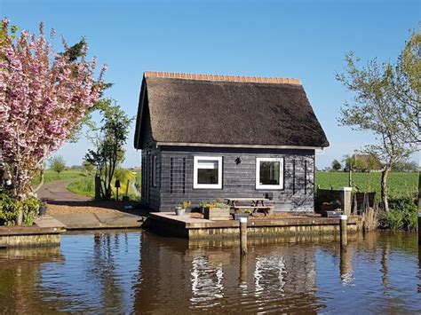 een charmant houten huisje aan het water met een bootje aanlegsteiger