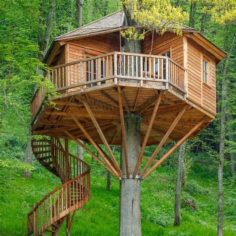 Een romantisch ingerichte boomhut met een tweepersoonsbed en een balkon.