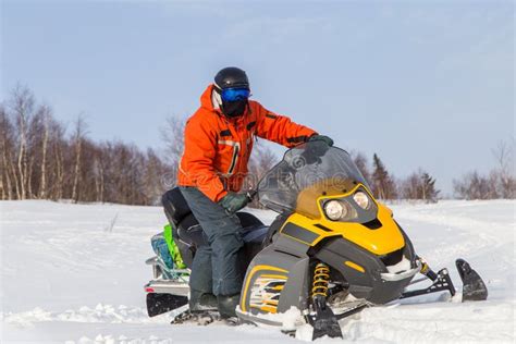 Een persoon op een sneeuwscooter die door een besneeuwd bos rijdt.