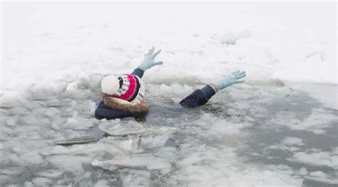 Een persoon die uit een wak in bevroren meer klimt, met een sauna op de achtergrond.