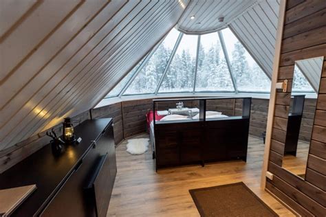 Interieur van een glazen iglo met uitzicht op de sterrenhemel.