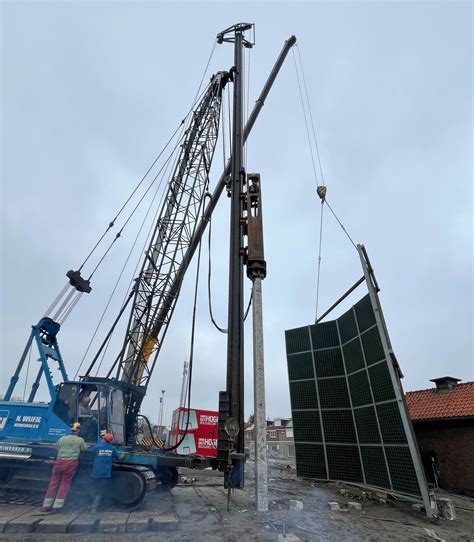 Een foto van de sloopwerkzaamheden bij De Vluchtheuvel, met een kraan die een gebouw afbreekt.