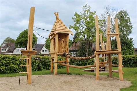 Kinderen die spelen in een buitenspeeltuin met klimtoestellen en glijbanen
