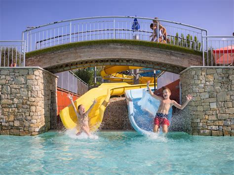 Gedetailleerde foto van het zwembadcomplex met glijbanen, waterval en ligstoelen.