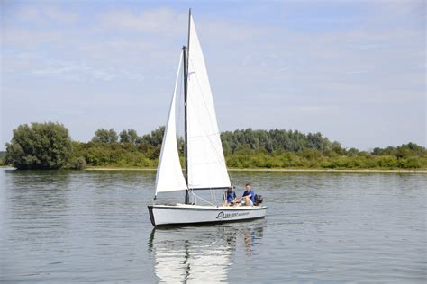 Een zeilboot op het Leekstermeer, met op de achtergrond het vakantiepark