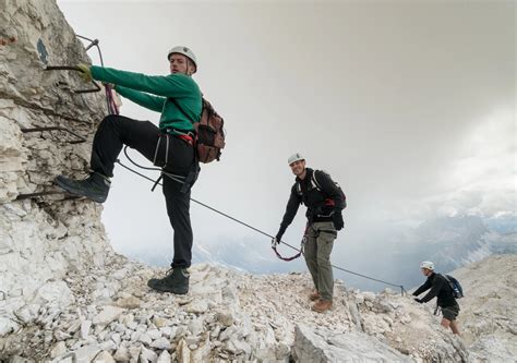 Een groep wandelaars beveiligd met via ferrata-uitrusting op een smal bergpad
