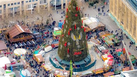 Overzicht van de kerstmarkt met kramen rondom de grote kerstboom