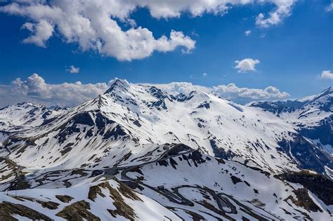 Panoramisch uitzicht op de Oostenrijkse Alpen rondom Leogang, met groene weiden en besneeuwde bergtoppen.