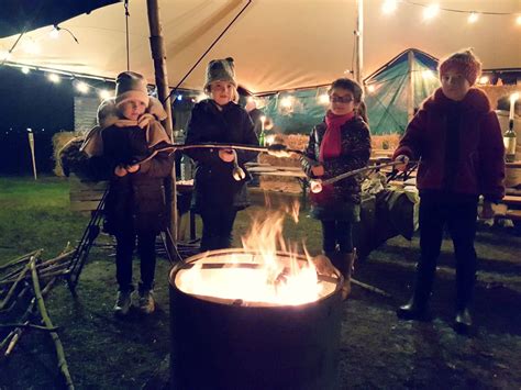 Kinderen die marshmallows roosteren boven een vuurkorf op een kerstmarkt.