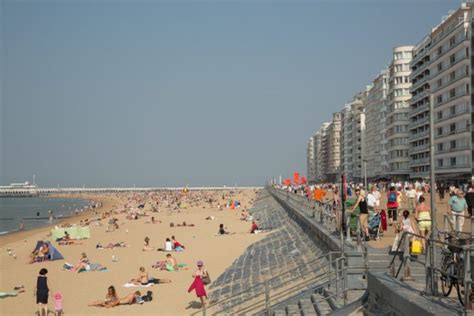 Foto van de Belgische kust met een brede boulevard en terrasjes.