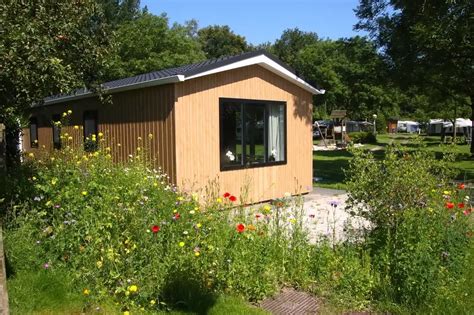 Foto van een chalet op vakantiepark Boschvoort, met op de achtergrond werkzaamheden voor de asielzoekersopvang.