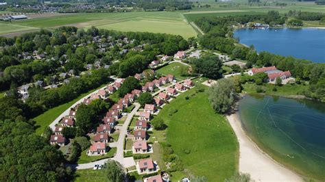 Buitenaanzicht van het vakantiepark met groene omgeving en huisjes tussen de bomen.