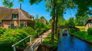Kano's varend door de grachten van Giethoorn met traditionele boerderijen op de achtergrond
