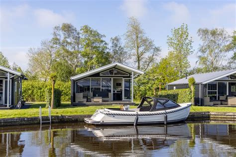 Een elektrische sloep aangemeerd bij een vakantiehuisje aan het water in Giethoorn